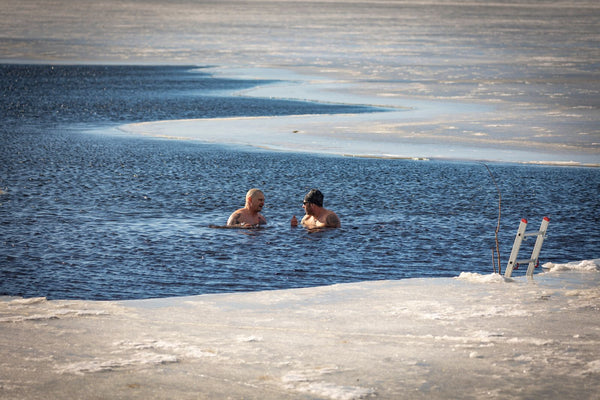 Two people resting calmly in cold open water in winter, a natural cold-water immersion