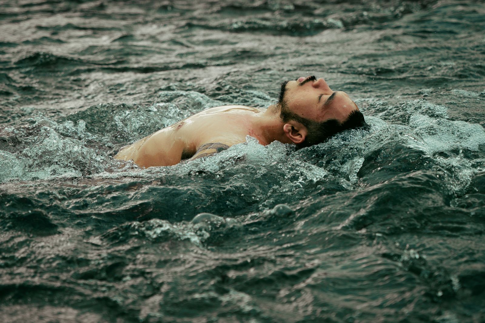 A person floating calmly in open water with eyes closed