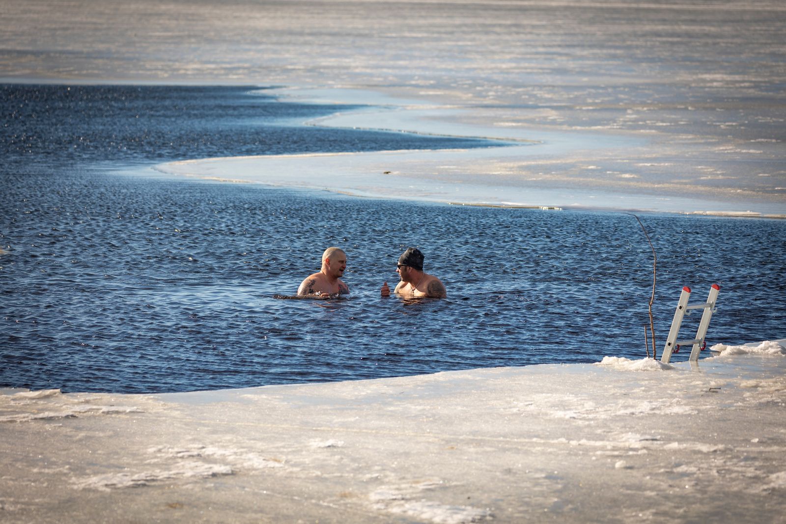 Two people resting calmly in cold open water in winter, a natural cold-water immersion