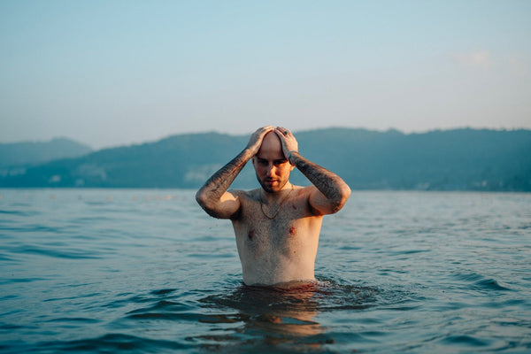 A man standing calmly in cold water with mountains behind